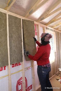 a woman is working on the insulation in her new home under construction with wood framing