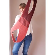 a woman holding up a knitted object in the shape of a flamingos head