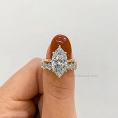 a woman's hand holding an engagement ring with a pear shaped diamond on it