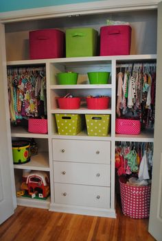 an organized closet with lots of colorful bins and baskets on the bottom shelf in front of it