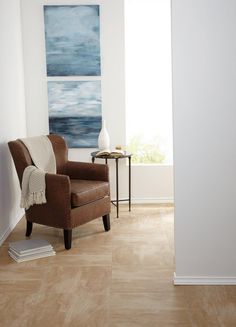 a brown chair sitting in front of a painting on the wall next to a table