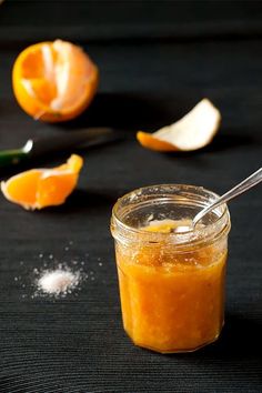 an orange peel is in a jar with a spoon next to it on a black surface