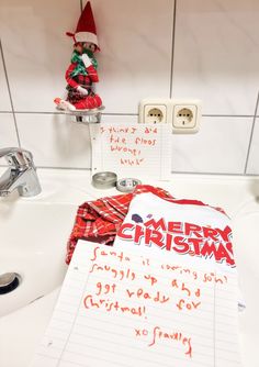 a christmas wish list is on the sink next to a toothbrush holder and soap dispenser