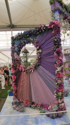 a large purple piece of cloth with flowers on it sitting under a tented area