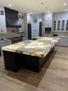 a large kitchen with an island in the middle of it and white cabinets on both sides