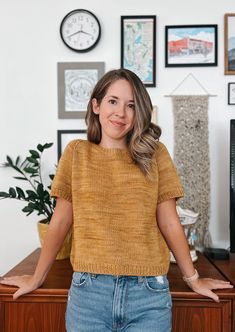 a woman standing in front of a desk with her hands on her hips and smiling at the camera