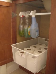 an organized bathroom closet with toilet paper and cleaning products on the shelf next to it