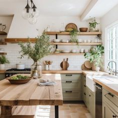 a wooden table sitting in the middle of a kitchen next to a sink and oven