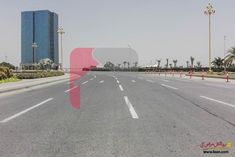 an empty street with buildings and palm trees in the backgrouds, on a sunny day