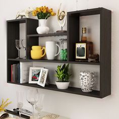 the shelves are filled with vases, cups and other items on display in front of a white wall