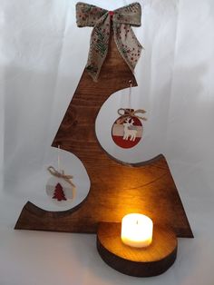 a wooden christmas tree with ornaments hanging from it's sides and a lit candle