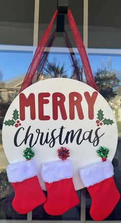 a merry christmas sign with stockings hanging from it's side and the words merry