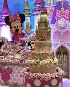 the cake is decorated with pink flowers and minnie mouse heads on it's side