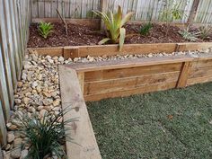 a wooden bench sitting next to a garden filled with lots of rocks and plants on top of green grass