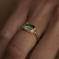 a woman's hand with a ring on it and an emerald stone in the middle