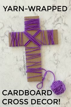 the yarn wrapped cross is next to a ball of string