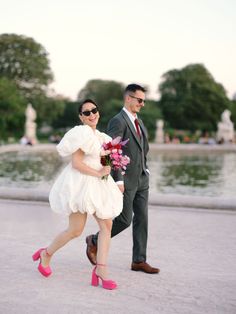 a man and woman walking in front of a fountain