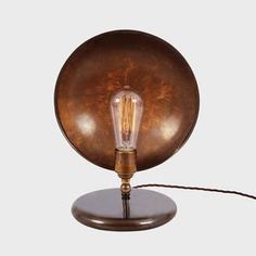 an old fashioned table lamp with a bulb on the base and a cord attached to it