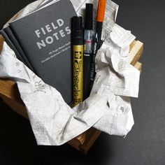 a pile of papers and pens sitting on top of a wooden box