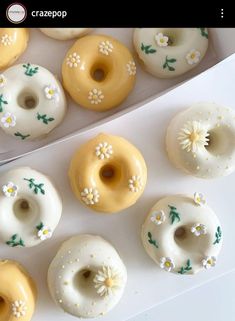 several glazed donuts with white and yellow frosting decorated with daisies on them