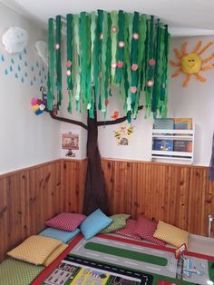 a bed room with a tree on the wall and various decorations hanging from the ceiling