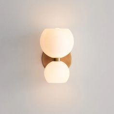 two white balls are on the wall next to a light fixture that is dimmer