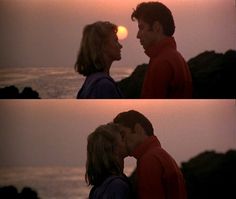 two people standing next to each other in front of the ocean at sunset or sunrise