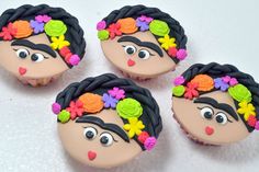 four decorated cupcakes with faces and flowers in the shape of frisbees