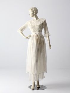 This an antique white dress from the late Victorian period. The sheer white dress features a ruffled neckline, three quarter sleeves, and a long skirt that wraps to create tiers. The bodice of the dress hooks to the skirt.  CONDITION The fair condition.  There are some holes in the bodice. There is wear around the waistband with snap closures missing. Currently held with safety pins. MEASUREMENTS Approximate FitXS Bust                     33"  ...  83.8 cm Waist              23"  ...   58.4 cm L Regency Style Cream Dress With Ruffles, Regency Victorian Dress With Ruffles In Cream, Victorian Ruffled Dress For Vintage Events, Cream Empire Waist Dress With Ruffles, Regency Style Empire Waist Dress With Ruffles, White Regency Style Prairie Dress With Ruffles, Vintage White Victorian Day Dress With Ruffles, Vintage White Victorian Dress With Ruffles For Daywear, Feminine Victorian Dress With Ruffles For Daywear