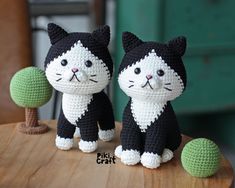 two crocheted black and white cats sitting next to each other on a table