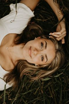 a woman laying in the grass with her eyes closed