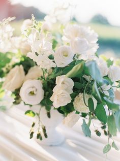 a white vase filled with lots of white flowers