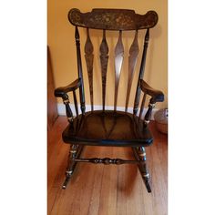 an old rocking chair with wooden slats on the back and seat, in front of a yellow wall