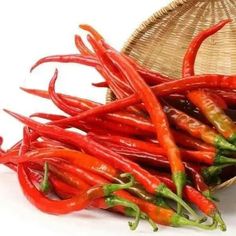 red hot peppers in a basket next to a straw hat