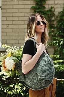 a woman carrying a green crocheted bag