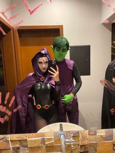 two people in costumes are taking a selfie with a cell phone while standing in front of a mirror