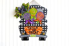 a trick or treat door hanger is decorated with colorful lollipops and candy