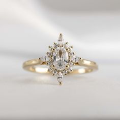 a yellow gold engagement ring with an oval cut diamond surrounded by smaller round and pear shaped diamonds