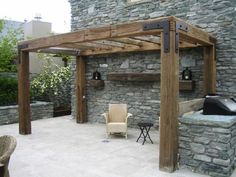 an outdoor living area with stone walls and wooden pergolated structures, including a grill