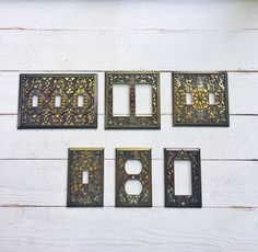 four metal switch plates mounted to the side of a white wooden wall with floral designs on them