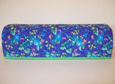 a blue and green flowered bag sitting on top of a white table next to a wall