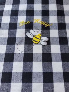 a black and white checkered shirt with a bee on it