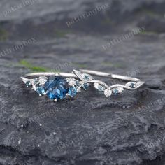 two rings with blue and white stones on top of a rocky surface in front of the camera