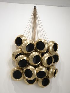 a bunch of black and gold balls hanging from a ceiling fixture in a white room