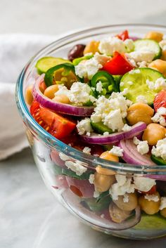 a glass bowl filled with vegetables and feta cheese