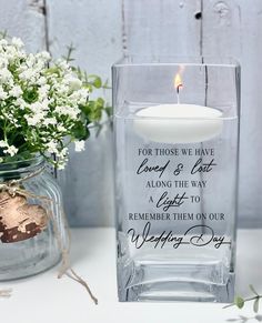 a glass vase with a candle and flowers in it