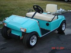 a light blue golf cart parked in a parking lot next to a white and black car