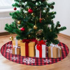 a small christmas tree with presents under it on a red and black checkered rug