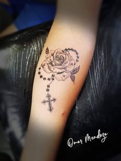 a rose and cross tattoo on the arm