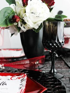 two black vases with white and red flowers in them on top of a table